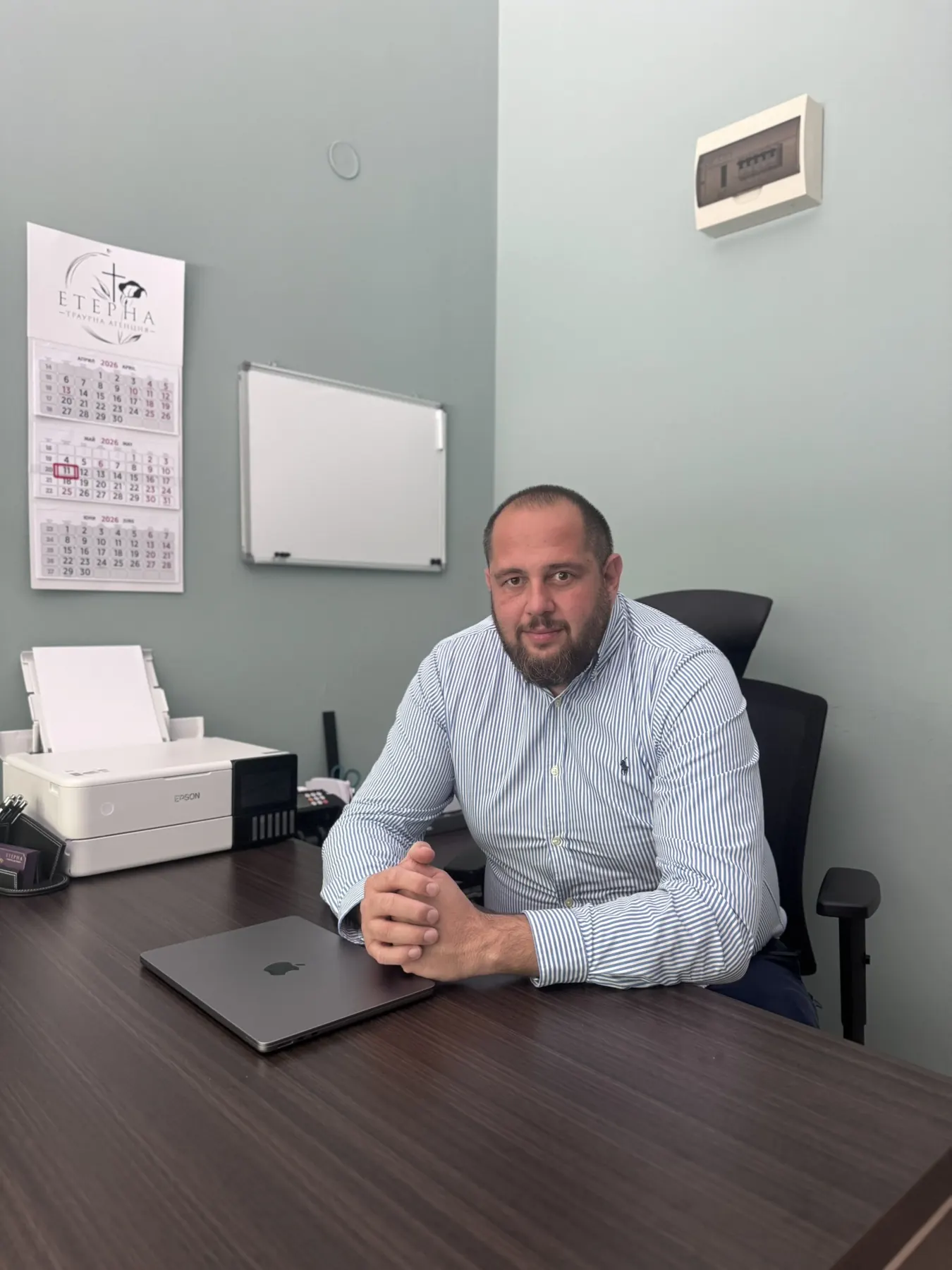 Служител на траурна агенция „Етерна“ зад бюрото в офиса