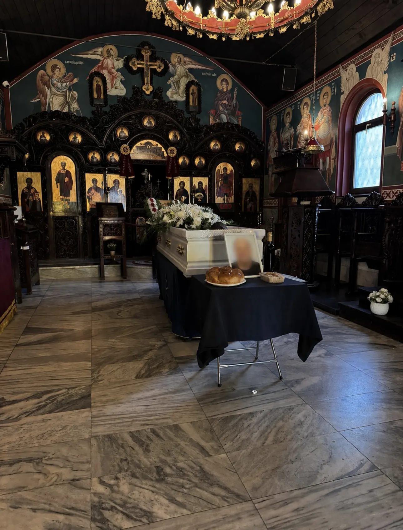 Бял ковчег с цветя и ритуален хляб пред иконостас в параклис с фрески